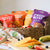 Hey! Chips fruit bites products in a basket with real mango, sliced strawberry, banana, and blueberry on the table.