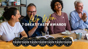 Group of people celebrating with text 'We Won 7 Great Taste Awards' and seven 'Great Taste' logos.