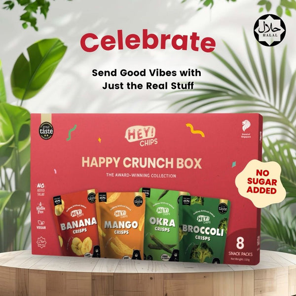 HEY! CHIPS Happy Crunch Box with various flavors on a wooden surface with greenery in the background.