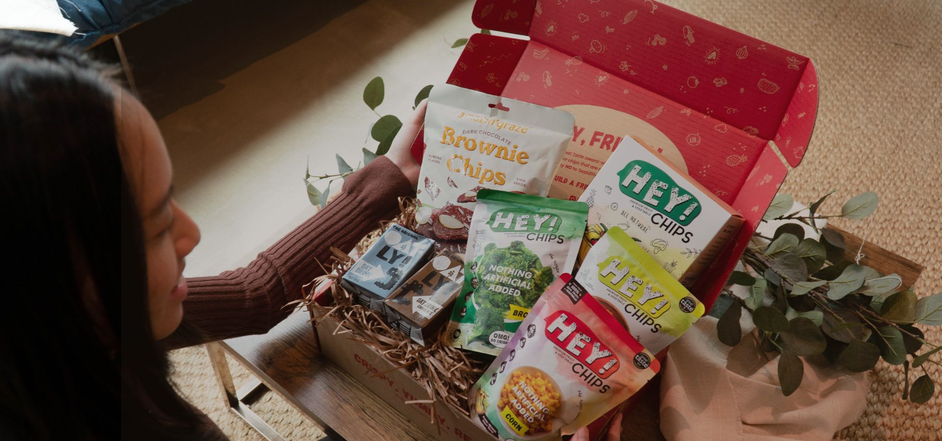 Person opening a box full of Hey! Chips packs.