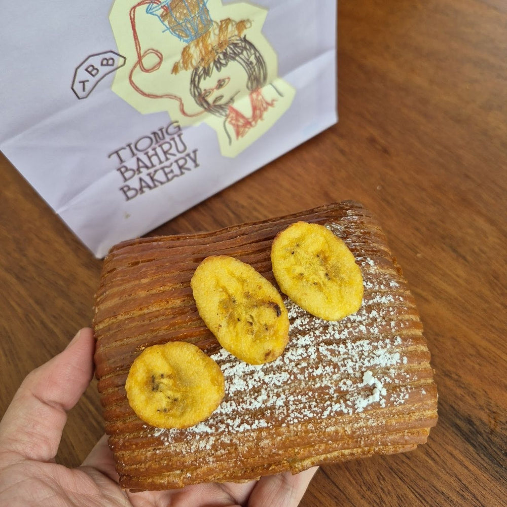 Wooden board with pastries and Hey! Chips banana, Tiong Bahru Bakery paper in the background