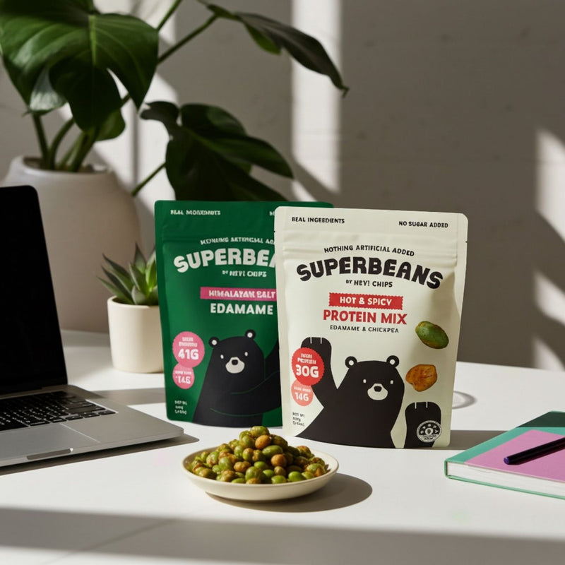 Superbeans protein mix packages on a desk with a laptop and snacks.